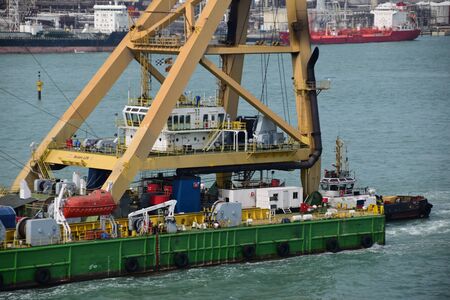 Detail of a big floating crane being pushed by a tug boat. A lot of equipment on deck.のeditorial素材