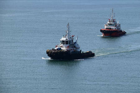Two tugboats inside port limits are about to be engaged in mooring operations.の写真素材