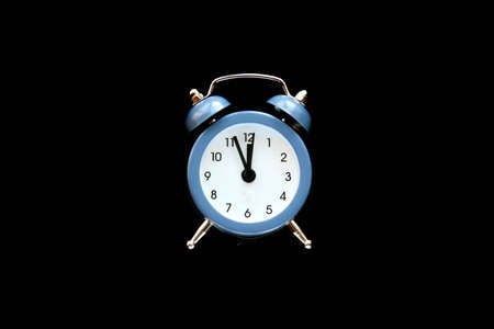 Blue vintage alarm clock shows 12 oclock isolated on black background. Wake up and hurry up. Hot sale, final price, last chance. Countdown to midnight new year. Copy space for your textの写真素材