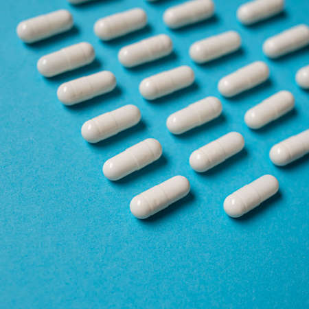 Many white capsule pills on a colorful background. Health supplements and medicinesの写真素材