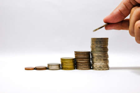 Male hand putting coins tacking and growing the saving money and business with white background concept.の写真素材