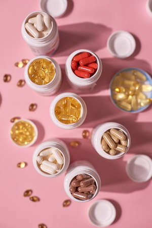 Many color pills capsules vitamins on pink background. Health supplements and medicinesの写真素材