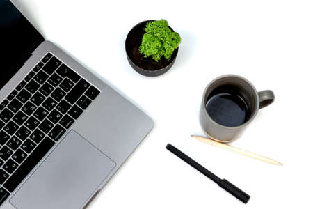 Top view white office desk table with blank notebook, computer laptop keyboard, pen, plant and other office supplies. with copy space, flat lay, isolated on white background. Coffee cupの写真素材