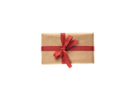 Christmas composition. Giftbox wrapped in craft paper with red ribbon isolated on white background. Christmas, winter, new year celebration concept. Flat lay, top view, copy spaceの写真素材