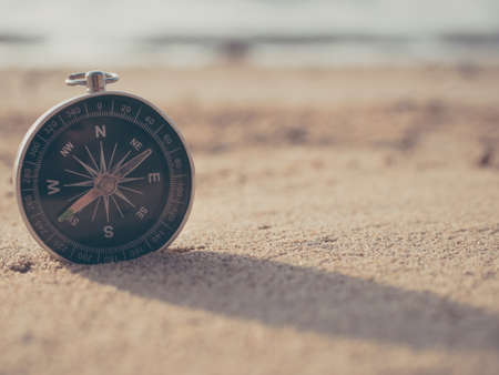 Compass is placed on the beach and sunshine in the evening sunsetの写真素材