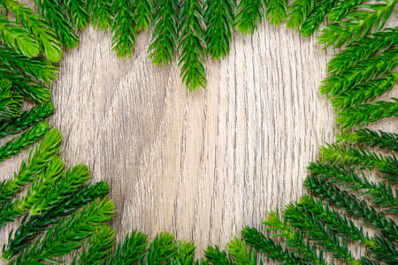 Green heart shape pine leaf on light wooden for background and texture. It use for decorative for online advertisement and merry christmas concept.の写真素材