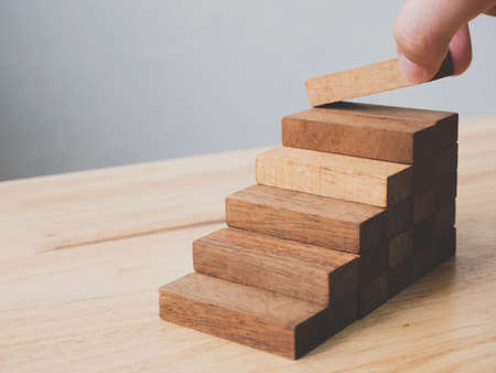 Hand arranging wood block stacking as step stair. Ladder career path concept for business growth success process, Copy spaceの写真素材