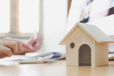 Wooden home model and key house on wood table with hand signing the document contract loan or mortgage property investmentの写真素材