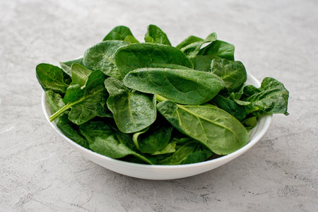 Clean food concept. Leaves of fresh organic spinach greens in a plate on a light background. Healthy detox spring-summer diet. Vegan Raw Food.の写真素材