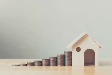 Property investment and house mortgage financial concept, Money coin stack with wooden houseの写真素材