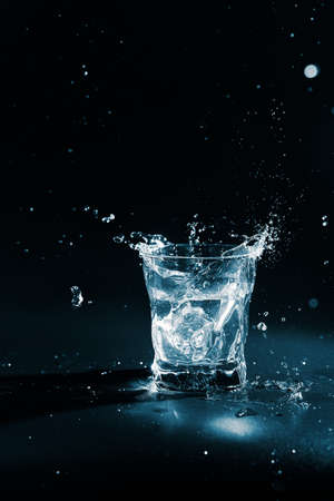 Pure water splashing out of glass on black backgroundの写真素材