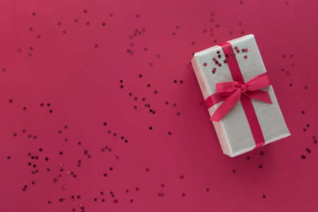 Christmas composition. Giftbox with red ribbon and confetti decorations on pastel paper colorful background. Christmas, winter, new year celebration concept. Flat lay, top view, copy spaceの写真素材