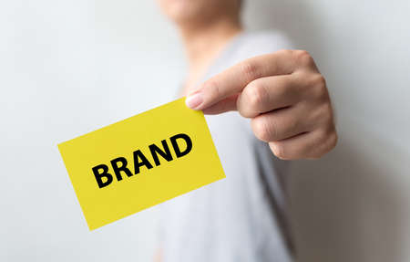 Man holding yellow card and word BRAND. Brand building for success conceptの写真素材