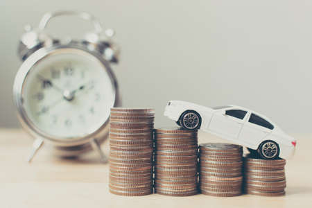White miniature car on money coin stack growth with clockの写真素材