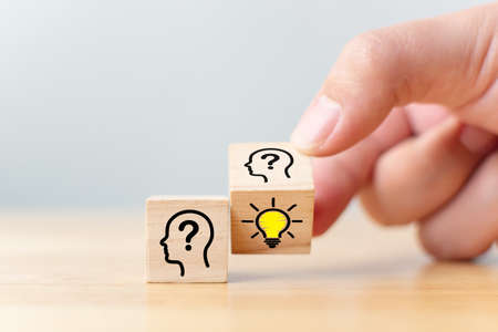 Concept creative idea and innovation. Hand flip over wooden cube block with head human symbol and light bulb iconの写真素材