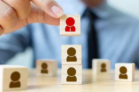 Human resources management and recruitment business build team concept. Businessman hand putting wood cube block on top with iconの写真素材