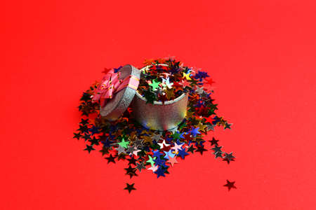 Blue present box with pink bow and confetti on a red background.の写真素材