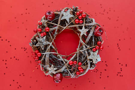 Christmas Wreath Made of branches decorated with gold wooden stars and red berry bubbles isolated on red background. Creative diy craft hobby. Making handmade craft christmas decorations bannerの写真素材