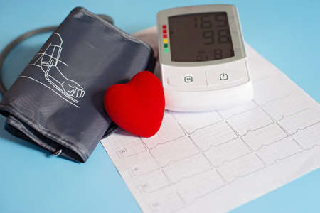 Red toy heart and tonometer on the background of a cardiogram. Healthcare concept. Cardiology - Caring for the Heart..の写真素材