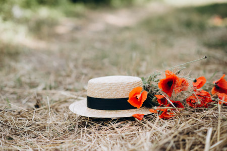 Bouquet of poppy flowers with a linen hat on a golden dry straw. Place for insertion of text. Summer concept.の写真素材
