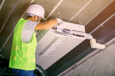 Male Technician Repairing Air Conditioner in uniformの写真素材