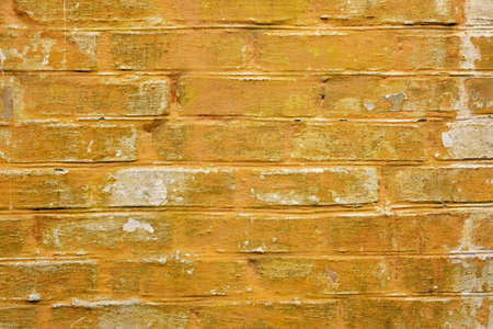 rough yellow brick wall with peeling paint. texture for backgroundの写真素材