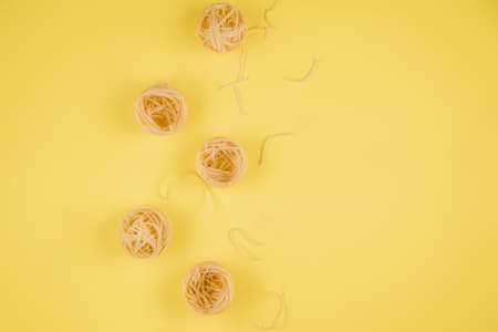 Raw tagliatelle paste isolated on yellow background.の写真素材