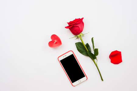 One dark red rose and mobile phone isolated on white backgroundの写真素材