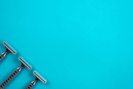 Three disposable razors are arranged diagonally on a blue background.の写真素材
