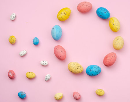 Easter background, shape with a multi-colored eggs lie on a pink table. - Copyspace