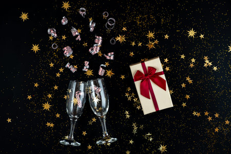 In anticipation of the holiday. Glasses, gold sequins and candies on a black background.