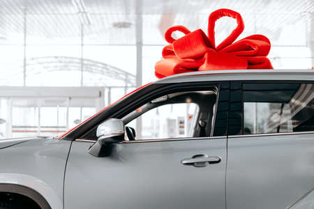 The new car is wrapped in a red bow. Beautiful gift conceptの写真素材