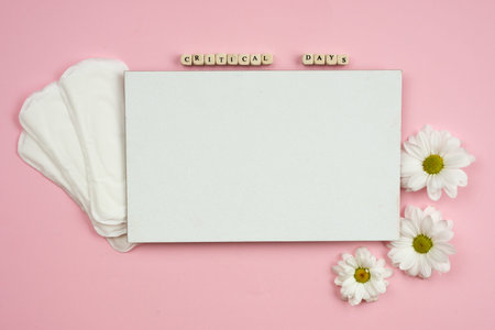 Female pads and white piece of paper on a pink background