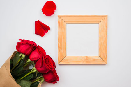 On a white background there are beautiful red roses and a frame. Place for text, copy spaceの写真素材