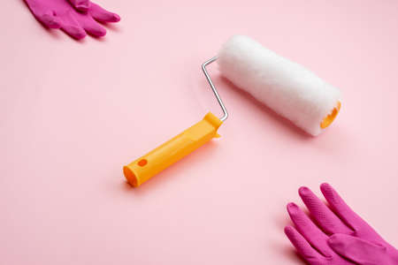 paint roller and latex gloves lying on diagonal on pink backgroundの写真素材