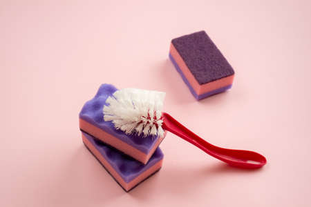 Household brush ang kitchen sponge lying on pink backgroundの写真素材
