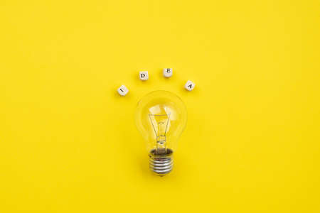 bulb on yellow background next an inscription idea - Imageの写真素材