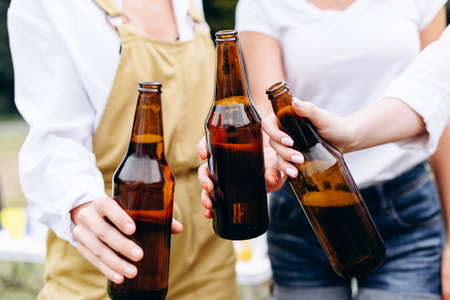 A company of friends raising a bottles - Closeup handsの写真素材