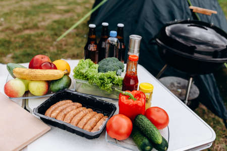 Beer, sausages and fresh vegetables on the table outdoor. - Campingの写真素材