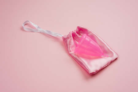 Menstrual silicone cup lying on silk bag on pink backgroundの写真素材