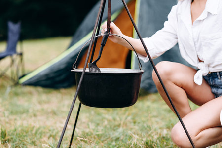 Young woman cooking in the camping sitting next the bonfire - cropping imageの写真素材
