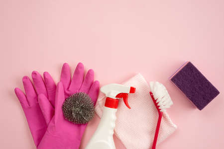 Household brush, kitchen sponge, cleaning spray and rag lying on pink backgroundの写真素材