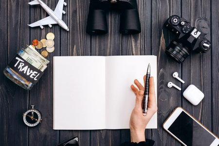 Top view of map with camera, bank with promotion, binoculars, compass, headphones, phone, sunglasses, travel conceptの写真素材