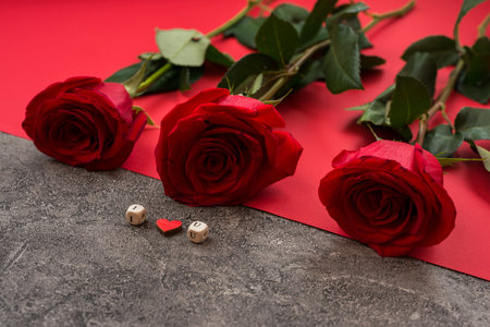 On a gray-red background there are red roses and cubes with letters laid out, the phrase I love you