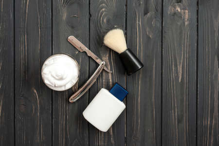 Top view, on a dark wooden background Shaving tools: after shave balm, razor, shaving brush and shaving creamの写真素材