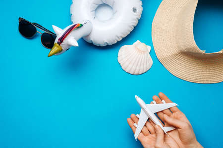 On a blue background are a hat, sunglasses, an oversized circle, in the hands of an airplaneの写真素材