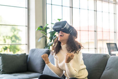 Latin woman using a virtual reality headset on sofaの写真素材