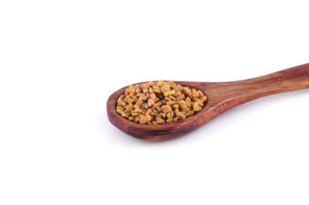 Fenugreek seeds in wooden spoon isolated on white backgroundの写真素材