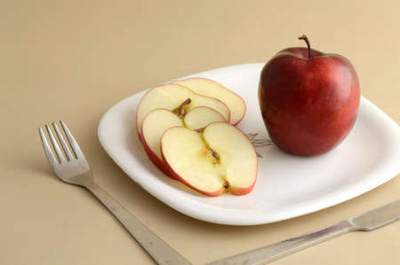 Delicious apple and slice in white plate with knife and forkの写真素材