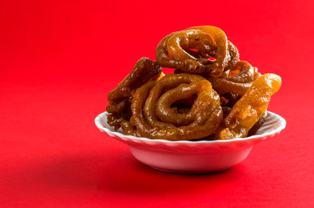 Indian sweet jalebi, indian dessert jalebi or imarti or imarati or jilbi on red backgroundの写真素材